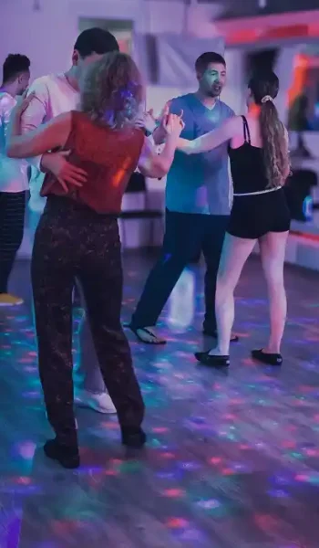 Пари танцюють Парна бачата в Києві на занятті в Ola Dance Studio Київ в атмосферному кольоровому освітленні