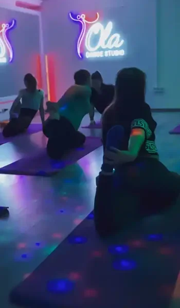 Група на занятті стретчингу в Ola Dance Studio Київ, виконують розтяжку на підлозі в атмосферному освітленні